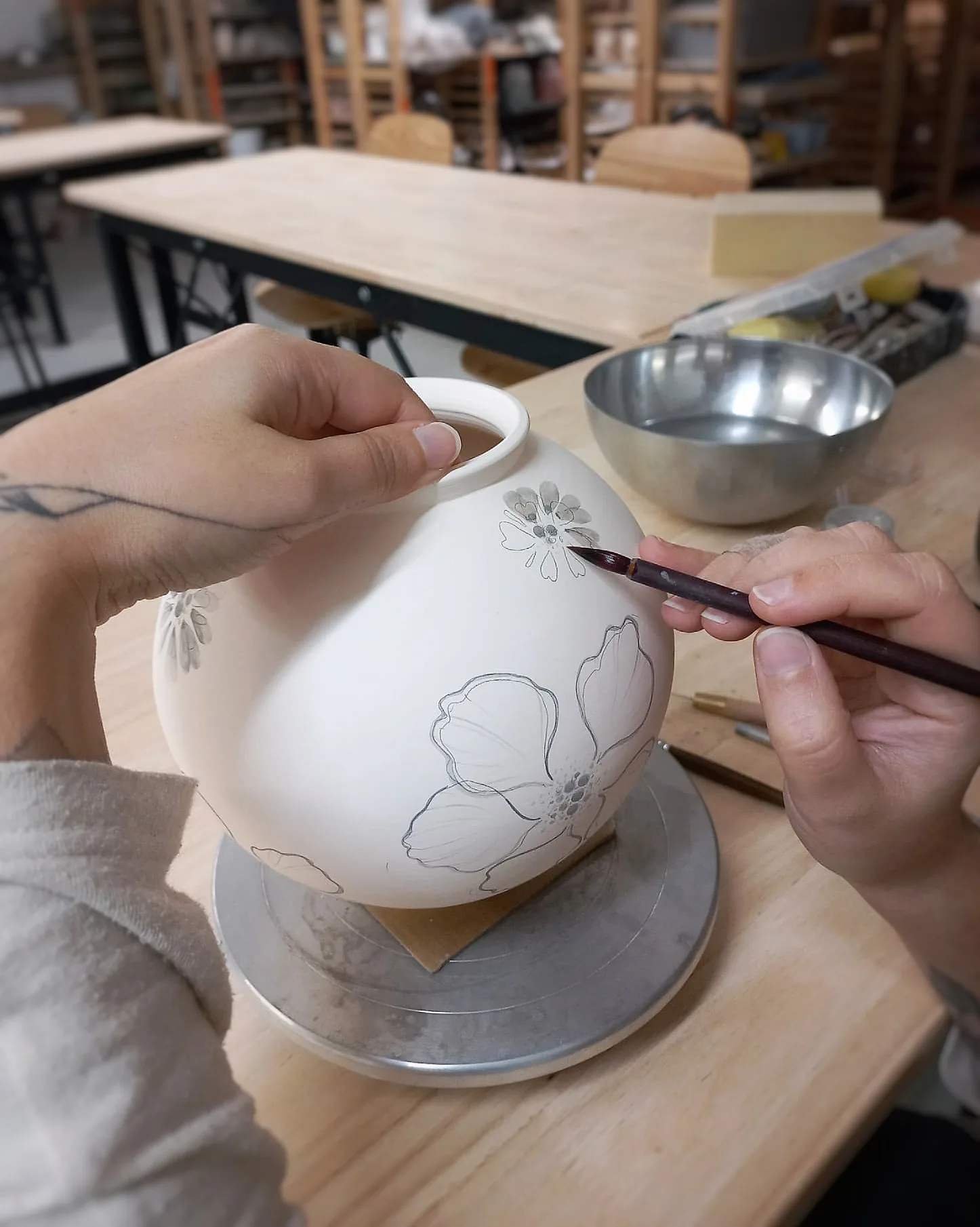 Peinture au pinceau d'un motif floral sur une pièce en porcelaine
